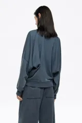 Buzo de algodón color negro con efecto gastado, corte globo y mangas largas ranglán. Presenta un logo bordado discreto en el pecho.