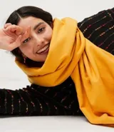 Chalina de poliéster color amarillo mostaza, de textura suave y terminaciones deshilachadas.