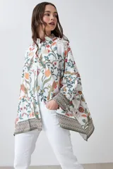 Camisa oversized con estampa floral en tonos naranja, verde y rojo sobre fondo blanco, con cuello clásico y cierre frontal con botones.