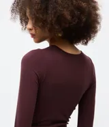 Body de manga larga con cuello redondo, confeccionado en tejido de poliamida y elastano sin costuras. Presenta un diseño ajustado al cuerpo con cierre inferior mediante botones de presión.