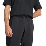 Pantalón deportivo New Balance de corte jogger, color negro, con cintura elástica ajustable mediante cordón, puños elásticos en los tobillos y logo de la marca bordado en la pierna izquierda.