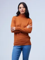 Polera tejida de hilado fino color naranja óxido, con cuello tortuga y manga larga. Los puños tienen apliques de botones dorados.