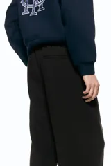 Pantalón relaxed fit color marrón, confeccionado en tejido suave, con cintura elástica ajustable mediante cordón, bolsillos laterales discretos, bolsillo posterior insertado y piernas rectas con pliegues frontales y traseros.
