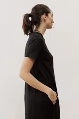 Vestido midi negro con diseño de manga corta, cuello redondo y bolsillos laterales, corte amplio y fluido.