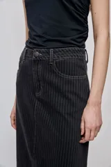 Falda larga de denim negro con diseño a rayas verticales y calce recto, tiro medio, bolsillos y cierre con botón.
