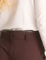 Pantalón de corte recto y entallado, estilo ankle, en color marrón. Presenta cintura con detalle en cuero sintético, pasadores funcionales, cierre frontal con broche y bolsillos delanteros.