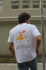 Remera blanca de algodón con estampado floral multicolor en la espalda y la frase "Más flores, menos drama".