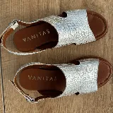 Sandalias de cuero color blanco con textura tipo reptil, plataforma marrón y hebilla metálica plateada.