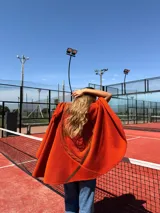 Capa color naranja de lana merino con cuello redondo y diseño con pespuntes en la espalda.