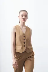 Chaleco sastrero color marrón oscuro, con escote en V, cierre frontal de botones y pinzas de entalle.