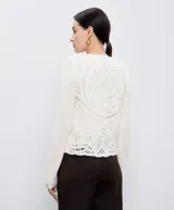 Chaqueta de hilo color crema con cuello redondo, mangas largas y cierre frontal con botones dorados. Diseño calado de crochet en la parte delantera y trasera.