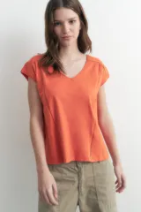 Remera naranja de corte recto, con cuello en V y mangas cortas. Presenta detalle de vainillas en los laterales y en los hombros.