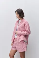 Camisa de calce relajado y silueta amplia con estampado cuadrillé en tonos rojo y blanco. Presenta cuello clásico, cierre frontal mediante botones y mangas largas.