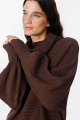 Sweater de punto acanalado color marrón, con cuello alto tipo polerón, mangas largas abullonadas y puños anchos.
