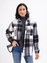 Sobrecamisa de franela con estampado de cuadros grandes en tonos blanco y negro. Presenta cuello camisero, cierre frontal con botones, mangas largas con puños abotonados y bolsillos frontales con solapa.
