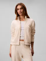 Campera de felpa con cierre de Calvin Klein, color beige, con cuello alto, bolsillos laterales, puños y bajo elásticos, y logo bordado en el pecho.