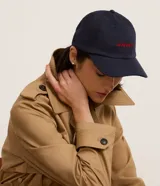 Gorra azul marino de sarga con visera curva, ajuste trasero y bordado rojo con la palabra "amour" en el frente.