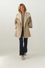 Tapado de largo medio en color arena, con diseño abierto y cuello solapa amplio. Presenta terminaciones envivadas en tono contrastante y mangas tres cuartos. Confeccionado en lana fina sin teñir.