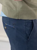 Pantalón chino azul marino de corte slim fit, confeccionado en gabardina con 77% algodón, 20% de algodón reciclado y 3% elastano. Presenta bolsillos delanteros y traseros. Tiene un lavado final con enzima ácida que le da un aspecto desgastado.