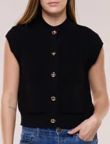 Chaleco de punto waffle color negro, sin mangas, con cuello alto, cierre frontal de botones metálicos dorados y bolsillos frontales aplicados.