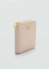 Billetera mediana de efecto piel en color beige, con cierre de cremallera perimetral y placa metálica dorada con el logo de la marca en el frente.