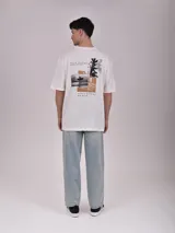 Remera color verde petroleo, de manga corta y corte oversize, con estampa en el pecho izquierdo que dice 'Noble Origins' junto a un diseño floral.