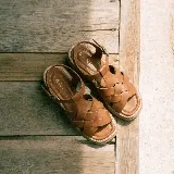 Sandalias de cuero vacuno color marrón, con diseño de tiras cruzadas en la parte delantera, tira ajustable en el talón con hebilla metálica y suela de plataforma con costura visible.