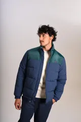 Campera puffer con diseño bicolor, cuerpo en azul marino y canesú superior en verde oscuro. Presenta cuello alto, cierre frontal completo y puños elásticos.