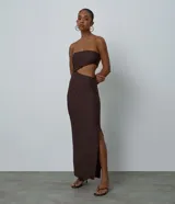 Vestido largo texturizado color marrón, sin mangas, con escote palabra de honor (strapless), recorte cut out en la cintura y tajo lateral en la falda.