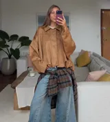 Campera tipo bomber oversized con efecto gamuza, cuello clásico, cierre frontal oculto y hombros estructurados.
