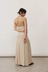 Vestido largo negro de corte al cuerpo con cuello halter y detalle de hebilla metálica dorada en el hombro con tira drapeada.