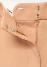 Pantalón de tiro medio con diseño recto y largo, confeccionado en tejido de lyocell. Presenta cierre delantero con botón, gancho y cremallera ocultos, trabillas en la cintura y detalle de pinzas frontales. Incluye dos bolsillos laterales.