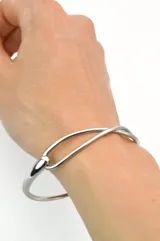 Pulsera rígida plateada de acero quirúrgico con cierre de gancho.