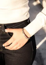 Pulsera esclava abierta de acero quirúrgico color plateado, con diseño de guarda griega.