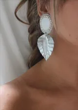 Aros colgantes plateados con forma de hoja y detalle de piedra blanca con strass.