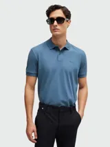 Polo de manga corta color azul petróleo, confeccionado en tejido piqué de algodón, con cuello y tapeta de dos botones. Presenta un logo bordado sutil en el pecho.