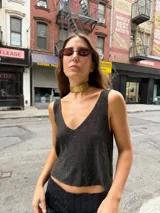 Top de tejido de punto negro con brillo, escote en V pronunciado y corte cropped.