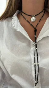 Collar de cuero azul con dije plateado en forma de caracol y detalles de cuentas plateadas. El collar tiene dos tiras que caen por el frente.