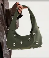 Bolso hobo verde militar con tachas plateadas, de tela suave y asa corta.