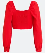 Blusa cropped roja de lino y viscosa, con escote cuadrado, mangas largas abullonadas y lazo frontal.
