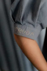 Chaqueta gris de silueta femenina con mangas abullonadas, cuello redondo y cierre frontal con botones forrados. Presenta detalles de bordado artesanal a mano en los hombros y solapas.