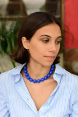 Collar de cuentas esféricas de color azul intenso, con cadena de acero quirúrgico en la parte posterior para regular su altura.