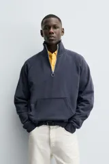 Sudadera de corte relajado color azul marino, con cuello subido y cierre frontal de cremallera. Presenta manga larga, bolsillo frontal tipo canguro y acabados en rib en puños y bajo.
