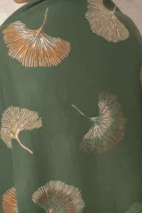 Pashmina reversible de textura suave y caída fluida, con diseño estampado de hojas de ginkgo biloba. Presenta un lado con fondo oscuro y otro con fondo claro, finalizando en ambos extremos con flecos cortos deshilachados.