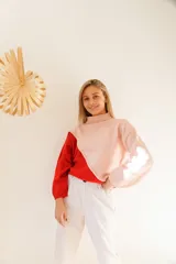 Sweater de lana de cordero italiano, con cuello cisne y diseño color block en rosa y rojo.