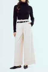 Pantalón marrón de corte ancho y talle alto, con pinzas frontales y bolsillos laterales.