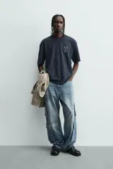 Camiseta relaxed fit color azul marino, con cuello redondo y manga corta. Presenta un estampado combinado a contraste en el delantero y la espalda. El estampado frontal es un texto en cursiva y un dibujo de tres figuras alargadas.