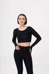 Top deportivo negro de manga larga, corte crop y escote redondo. Presenta aberturas para los pulgares en los puños.