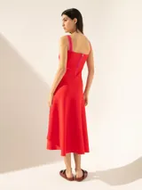 Vestido midi negro con breteles finos, escote recto y falda acampanada. Presenta detalles de ribete blanco en el escote y los breteles, y una línea vertical color ocre en el centro del frente.