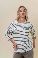 Remera de manga larga con diseño de rayas horizontales verdes sobre fondo crudo, cuello redondo con detalle de volado y cartera frontal con botones.